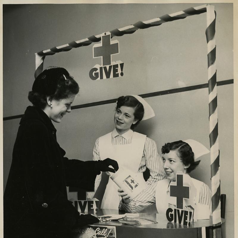 Nursing students Joan Huffine (C) and Lorraine Langhirt (R), co-chairs of the 1953 Red Cross Blood Drive, solicit donations at the registration booth