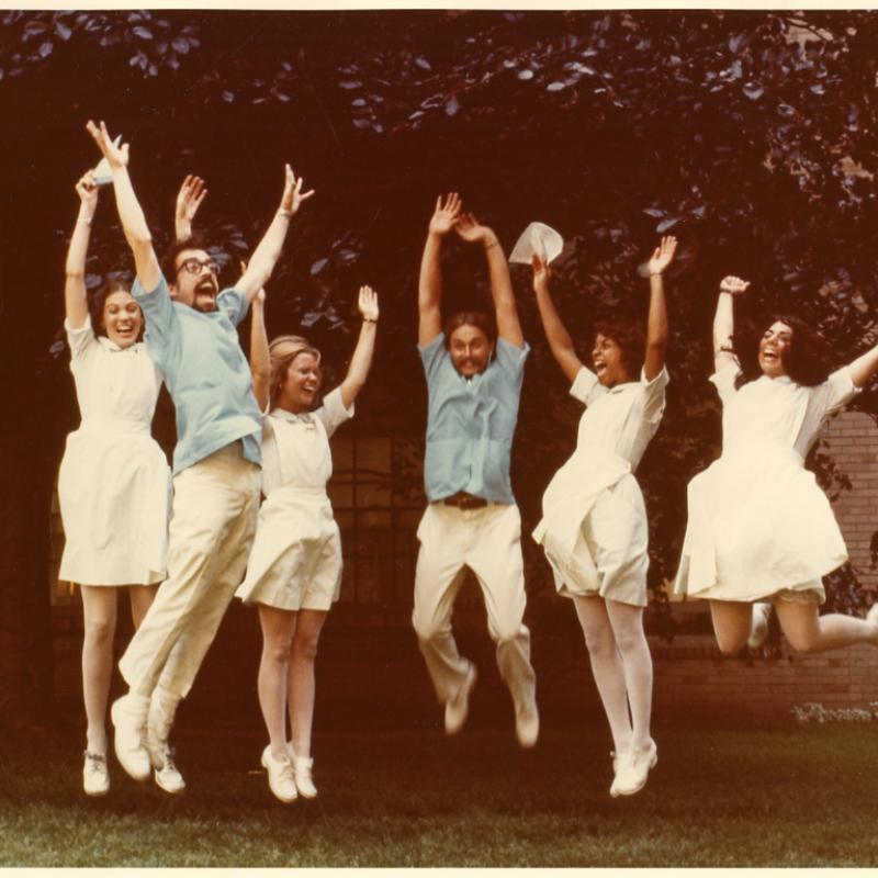 School of Nursing students jumping in the air in front of Maxwell Hall